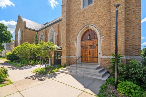 the front of a brick church with wooden doors and steps