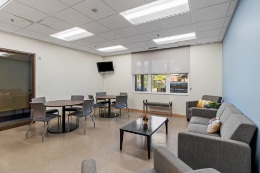 a common room with couches tables and chairs and a television