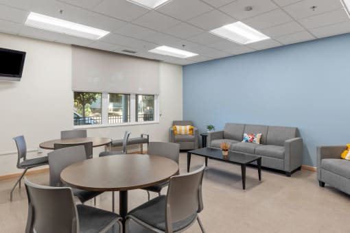 a waiting room with couches tables and chairs and a tv