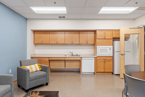 a room with a kitchen and chairs and a table