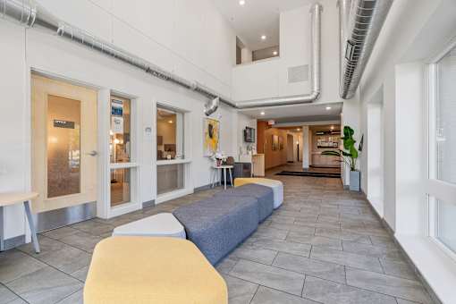a lobby with couches and chairs and a hallway with windows