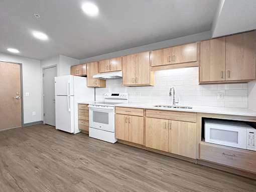 an empty kitchen with wooden cabinets and white appliances
