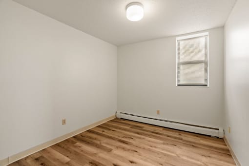 the living room of an apartment with wood flooring and white walls