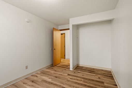 an empty room with wood flooring and a door to a hallway