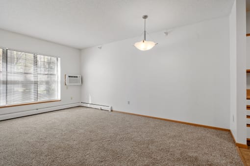 view of living room with large windows, hanging ceiling lamp and wall mounted air conditioner