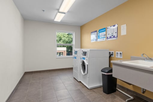 a washer and dryer in a laundry room with a sink and a window