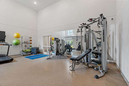 a home gym with weights and cardio equipment and a window
