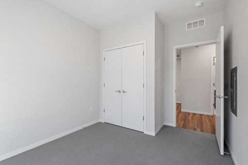 a bedroom with white walls and a door to a closet