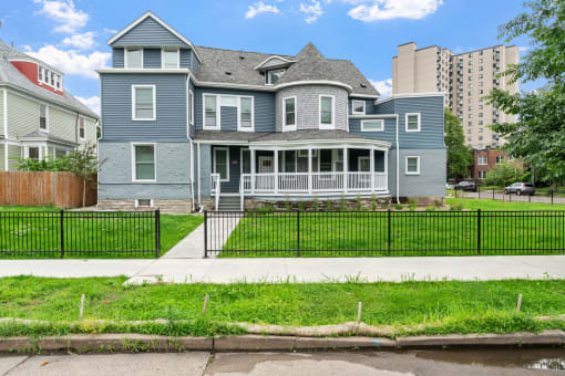a blue house with a yard and a black fence