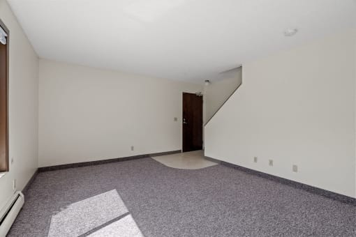 a living room with carpet and a door to a staircase