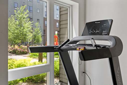 a treadmill in front of a window with a laptop on it