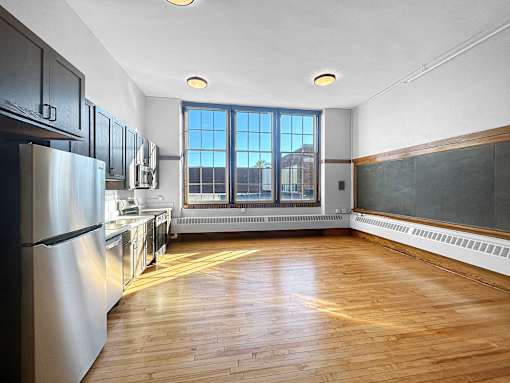 an empty kitchen with wood floors and a window