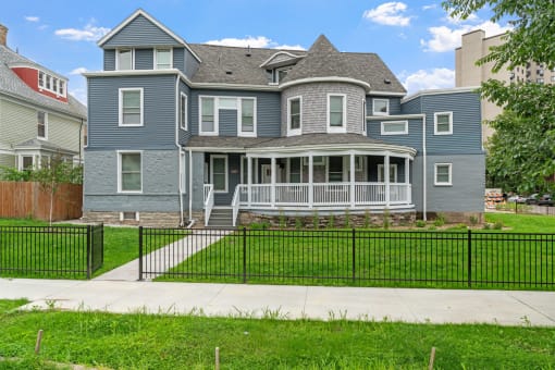 a blue house with a yard and a black fence