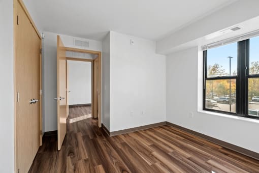 an empty room with wooden floors and a large window