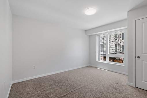 a bedroom with a large window and white walls