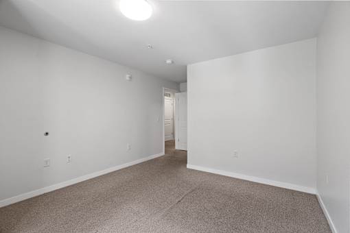 a bedroom with white walls and carpeting and a doorway to a closet