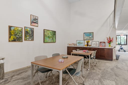 a dining room with tables and chairs and paintings on the wall
