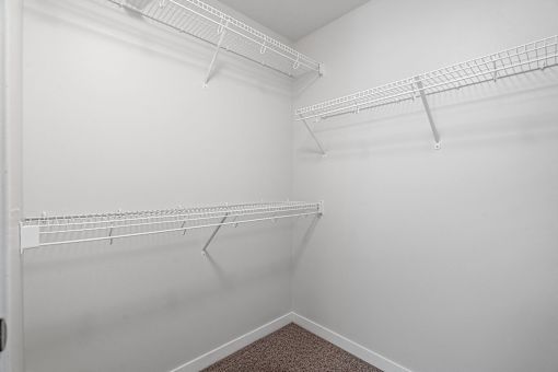 spacious closet with two shelves and two hanging racks in the corner of a room