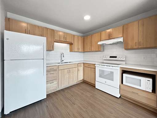 an empty kitchen with white appliances and wooden cabinets