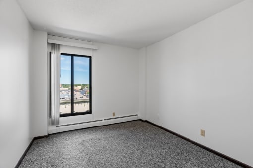 an empty living room with a window and white walls