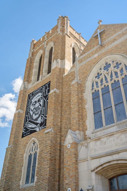 the side of a church with a steeple and a stained glass window