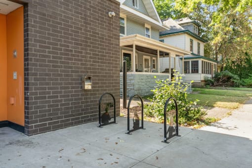 the front of a brick house with a sidewalk and bike racks