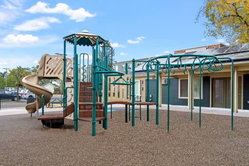 a playground with a slide and climbing equipment in front of a building