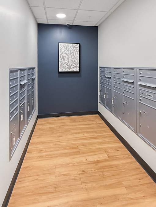 A long hallway with a row of mailboxes on the left and a row of mailboxes on the right.