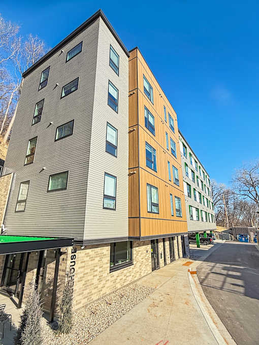 A modern apartment building with a mix of wood and stone exterior.