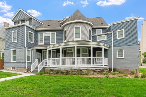 a blue house with a porch and a green lawn