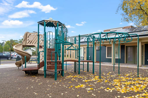a playground with a slide and climbing equipment in front of a building