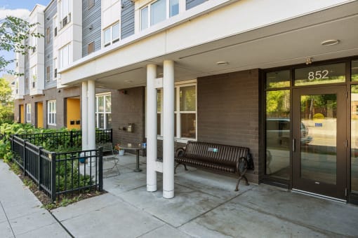 the entrance to a building with a sidewalk and a bench
