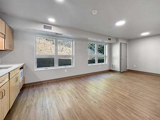 the living room and kitchen of an empty house with a large window