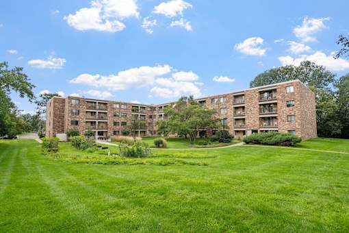 a large brick apartment building with green grass and trees