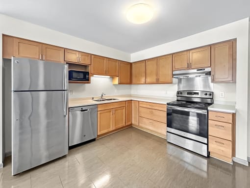 an empty kitchen with stainless steel appliances and wooden cabinets