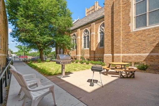 a patio outside of a church with a grill and picnic table