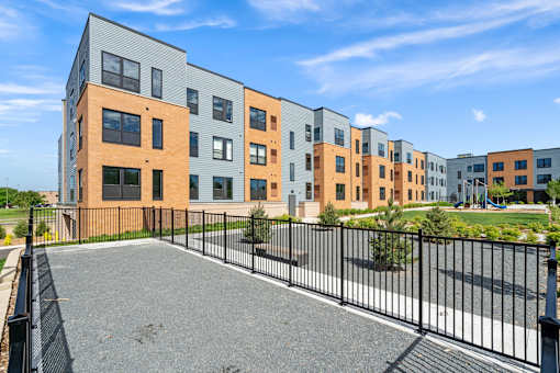 A row of modern apartment buildings with a black fence in front.