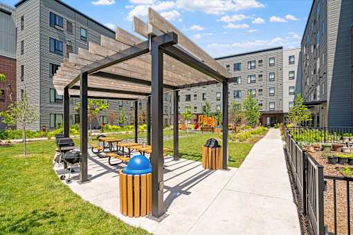 a park with benches and a pergola on a sidewalk