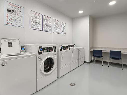 A laundromat with washers and dryers and instructions on the wall.