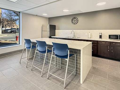 A kitchen with a bar area and blue chairs.