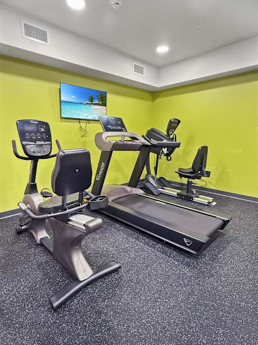 A gym with a yellow wall and a television screen showing a beach.