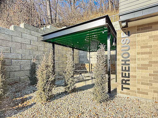 A treehouse with a green roof and a sign that says "TREEHOUSE" on the side of a building.