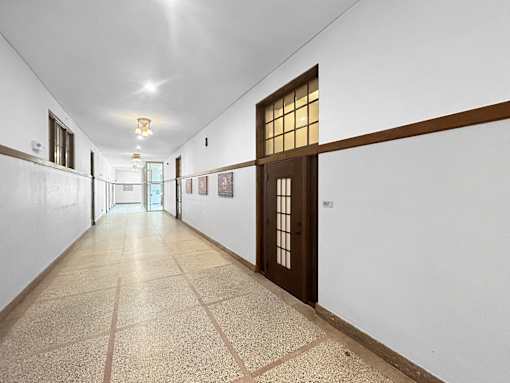a long hallway with white walls and a door in the middle