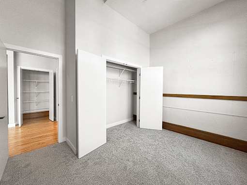 an empty room with white walls and doors to closets
