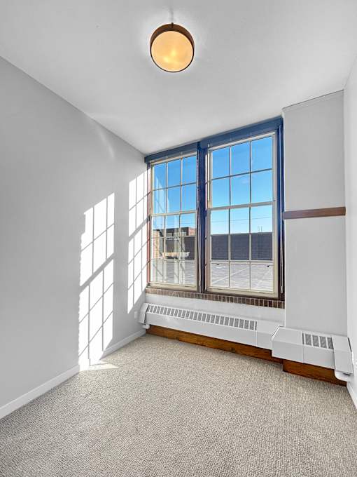 an empty room with large windows and a carpeted floor