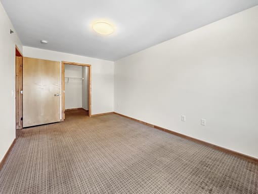 an empty room with a carpet and a door to a closet