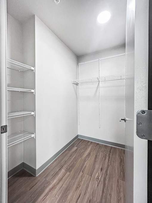 an empty room with white closets and wood flooring
