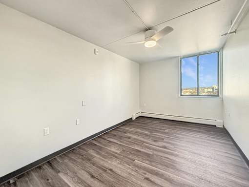 Empty room with a window and a ceiling fan.