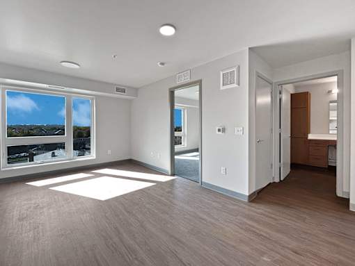 a renovated living room with a large window and wood flooring