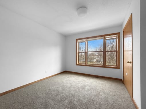 an empty room with a large window and carpet